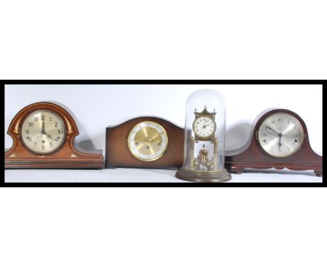 A group of four vintage clocks to include three Edwardian mantle clocks and a glass domed gilt brass anniversary clock.