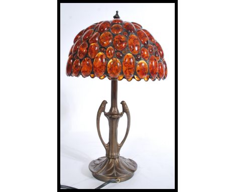 A vintage 20th century Art Nouveau style bronzed table lamp having a pressed circular base with amber type adorned shade. Mea