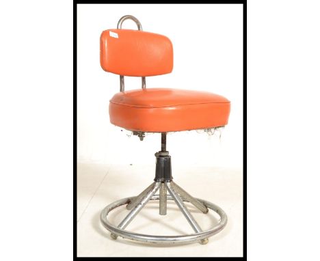 A vintage 20th century retro industrial machinist swivel chair raised on a chrome tubular base with orange vinyl seat and bac