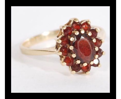 A hallmarked 9ct gold garnet stone cluster ring having a central faceted red stone with a halo of garnets. Weighs 2.5 grams s