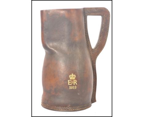 A vintage 20th century leather blackjack drinking tankard / ewer jug having gilt tooled Royal motif ERII 1953.&nbsp;