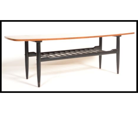 A vintage retro 20th century teak low coffee table having an ebonised lower tier with magazine rack joining the tapering legs