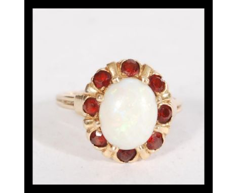 A 14ct gold opal and garnet cluster ring set with a large opal cabochon. Marked 14K tests 14ct gold. weight 4.4g. Size M.5.