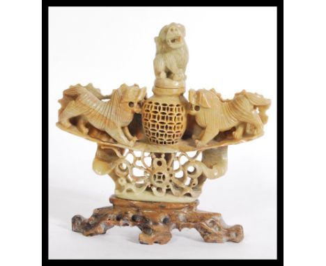 An early 20th century carved soapstone Chinese censer ding with open decoration having a fu dog finial lid flanked by temple 