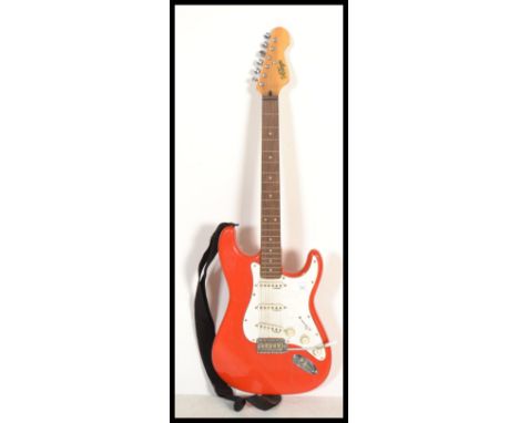 A vintage six string electric guitar having a shaped red body with white scratch guard.