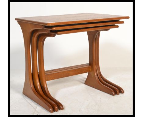 A set of three vintage 20th century Danish influence teak nest of tables in the manner of G-Plan. The panel tops raised on sp