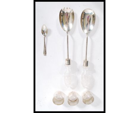 A pair of early 20th century silver hallmarked and cut glass handled salad servers along with three hallmarked silver napkin 