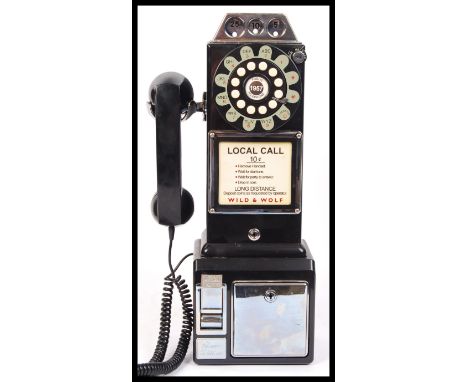 A Crosley 1950's retro vintage style plastic paywall phone in black having the rotary style numbers and telephone adaptor to 