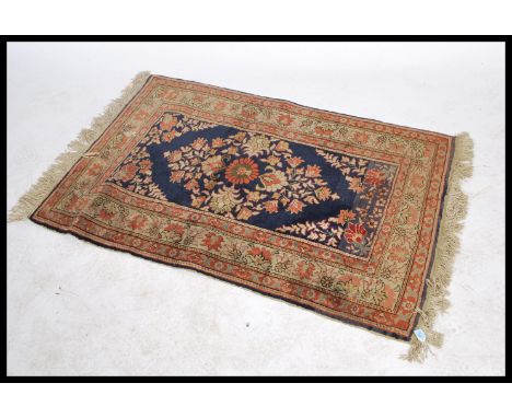 A vintage early 20th century Persian - Islamic floor rug decorated with plants and fauna to the central blue ground panel, wi