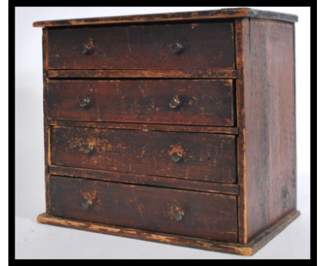 A vintage early 20th century apprentice piece miniature chest of four drawers. The bank of drawers having wooden handles. Mea