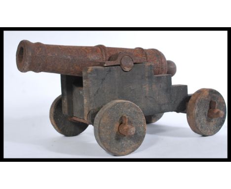 A vintage 20th century large cast iron floor cannon having wooden mounts. Measures 28 cm high, 38 cm wide and 56 cm deep.