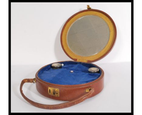 A vintage early 20th century round leather bag having fitted interior with two glass and silver hallmarked lidded pots.