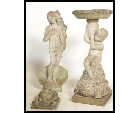 A group of vintage stone garden features to include a statue of a maiden stood on a open clam shell , a bird bath in the form