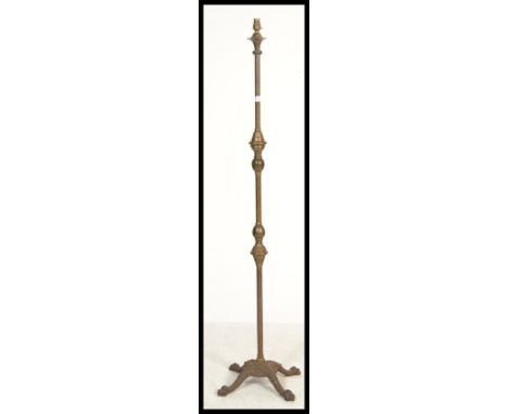 A 19th century brass and iron based standard lamp raised on a quadruped base with lion paw feet. The relief cast base set bel