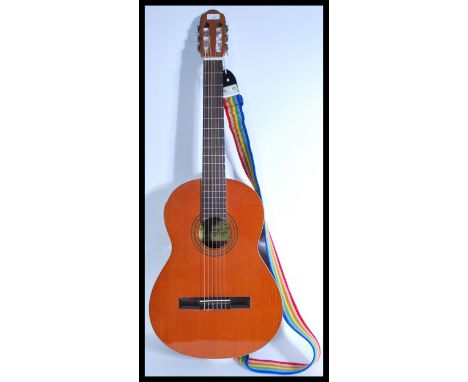 A vintage 20th Century six string acoustic guitar by Raimundo, paper label to centre with rainbow strap attached. Measures 10