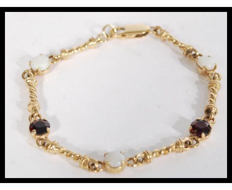 A hallmarked 9ct gold, garnet and opal set bracelet. Hallmarked Birmingham. Weight 10.1g. Measures 7.5inches.