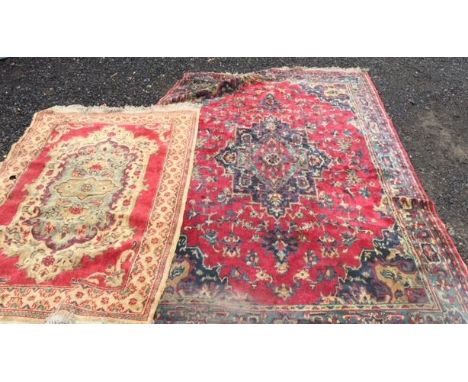 A pair of non matching vintage 20th Century floor rugs, the larger on red ground with central medallion and the smaller one o