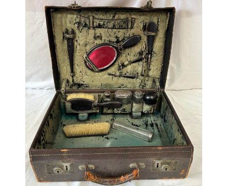 An Edwardian leather Vanity Case comprising of ebony brushes, tweezers, comb, mirror, shoe horn, powder compact, curlers, 4 x