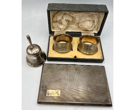 Hallmarked silver to include cigarette case, napkin rings and a .925 silver bell. Total weight 288gm.