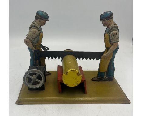 A vintage toy with men sawing a log. 14cm x 7.5cm.