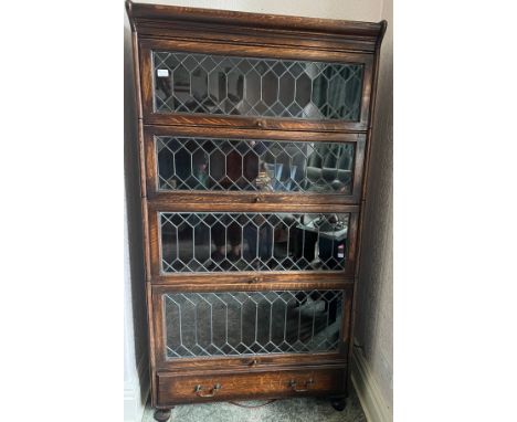 A four section oak globe wernike style bookcase with leaded doors over drawer. 167cm h x 87cm w x 36cm w.