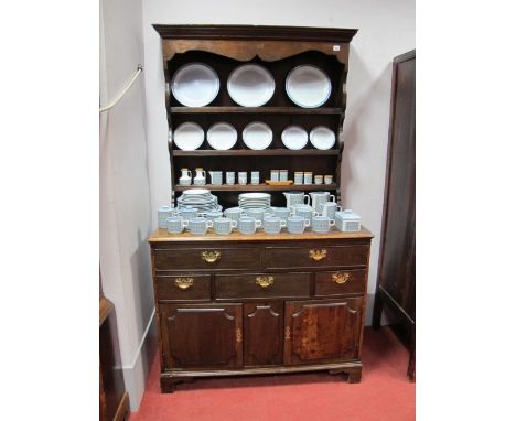 An XVIII Century Oak Dresser, the rack with stepped pediment and shaped cornice above three shelves to panelled back, the bas