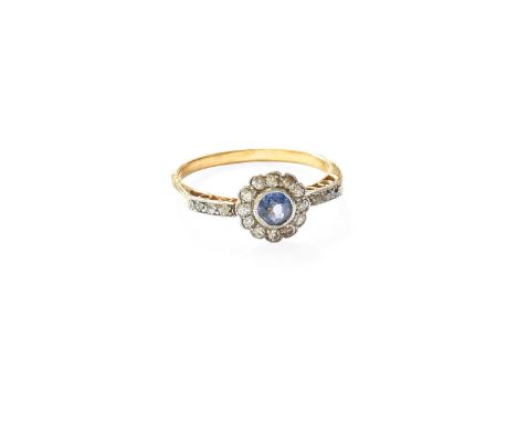 A Sapphire and Diamond Cluster Ring, the round cut sapphire within a border of old cut diamonds, in white millegrain settings
