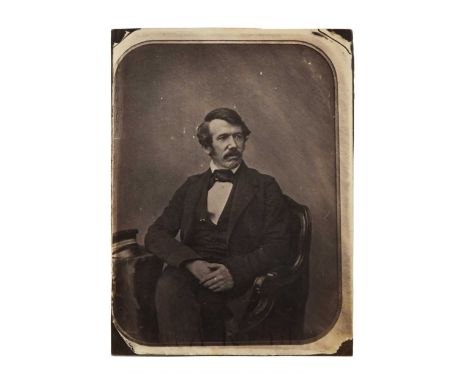 Dr David Livingstone (1813-73)early portrait photograph, showing borders, seated looking right with legs crossed and hands to