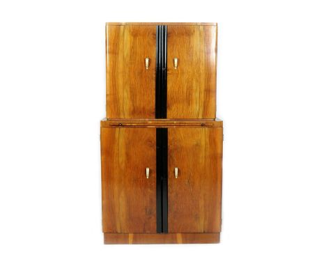 An English Art Deco walnut veneer cocktail cabinet, the top cabinet with hinged doors, internally set with mirrored glass, th