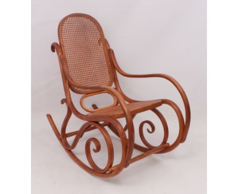A Thonet-style beech bentwood and caned rocking chair - first half 20th century, scrolling arms and supports, caned back and 