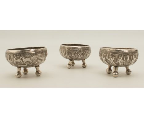 A set of three Persian&nbsp;white-metal tripod table salts - 19th century, the bowls with repouss&eacute; decoration depictin