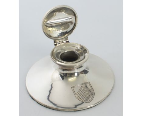 A large silver capstan inkwell with pen rest to the lid and original glass inkwell. Large chevron armorial to the front. Hall