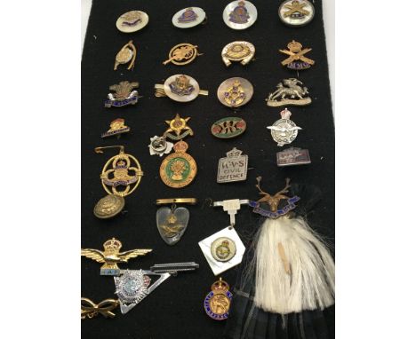 A collection of military regimental badges some mounted on mother of pearl with enamel decoration mounted on board.