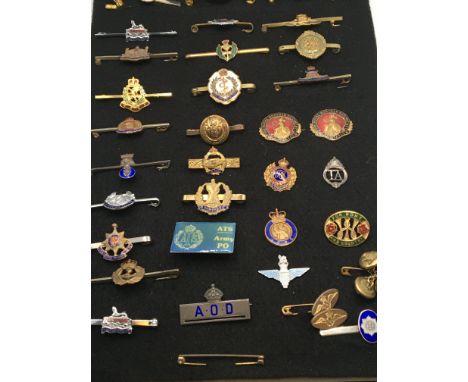 A collection of military regimental bar broaches and tie clips most with enamel decoration mounted on board.