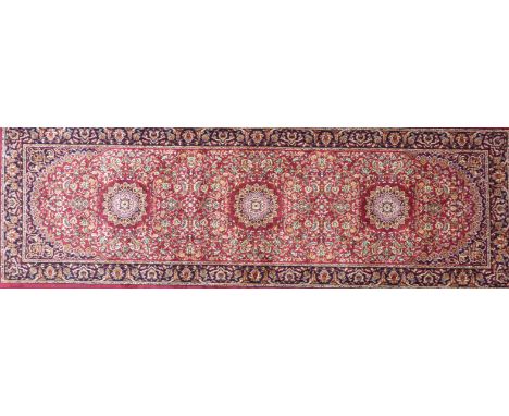 A Keshan runner on a mainly red ground
The central panel with three floral medallions with multiple floral decoration, surrou