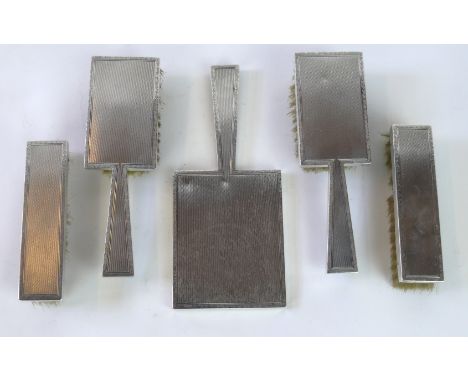 A George VI hallmarked silver five piece dressing table set
Each having engine turned decoration, comprising hand mirror, two