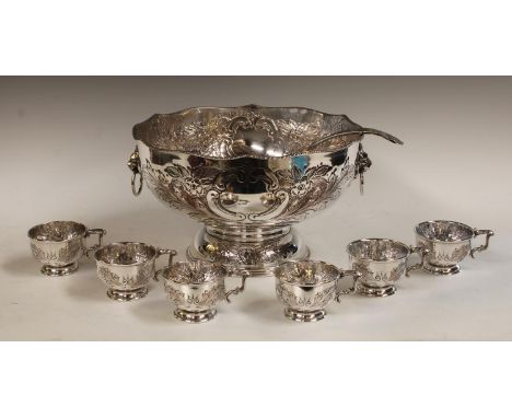 An EPNS punch bowl, embossed with foliate scrolls, two lion mask handles, ladle, six cups, 31cm diameter