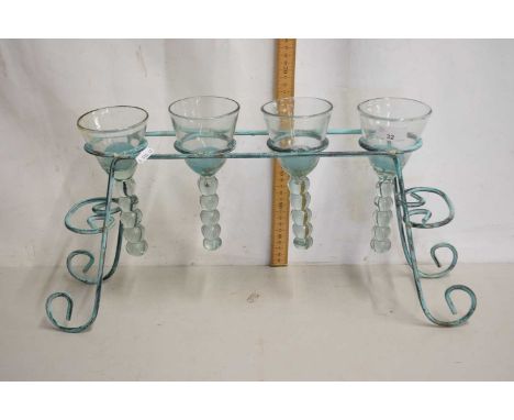 A modern iron framed and glass four light candle holder