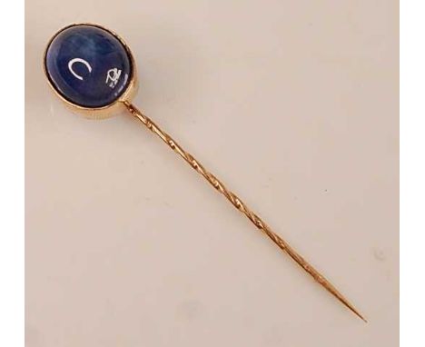 A yellow metal synthetic sapphire stick pin, featuring a verneuil cabochon cut synthetic star sapphire in a bezel setting, sy