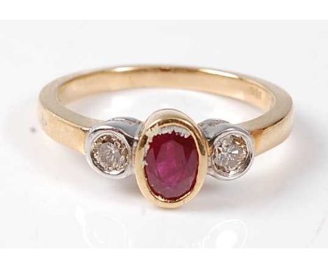 A yellow and white metal, ruby and diamond three-stone ring, comprising a centre oval faceted ruby with a round brilliant cut