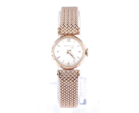 A 9ct yellow gold lady's Jaeger LeCoultre manual wind wristwatch, having a round silver baton dial and integral Milanese brac