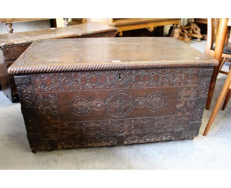 George I oak trunk, the hinged lid above a carved plank front with iron corner mounts and end handles, 101cms wide 