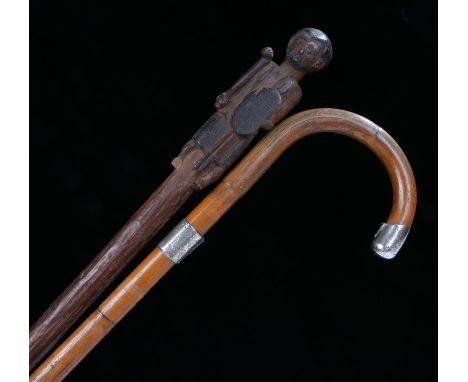 African tribal walking stick, the finial carved as a figure holding a club, shield and spears, the foot carved as a boot, 100