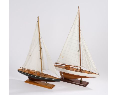 Two models of yachts, the first with a white and wood hull, sails raised, the second with a blue and wood hull also with sail