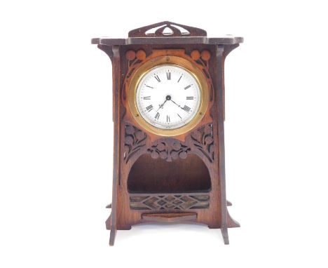 An Art Nouveau wooden cased mantel clock, circular enamel dial bearing Roman numerals, clockwork movement, the case of taperi