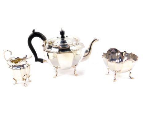 A George V silver three piece tea set, of fluted form, raised on four cabriole legs, comprising teapot, cream jug and sugar b