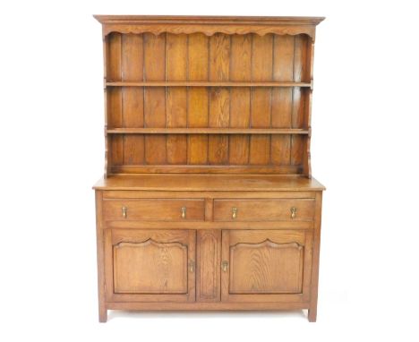 A Georgian style oak dresser, with a two shelf plate rack over two drawers above panelled cupboard doors, raised on square le