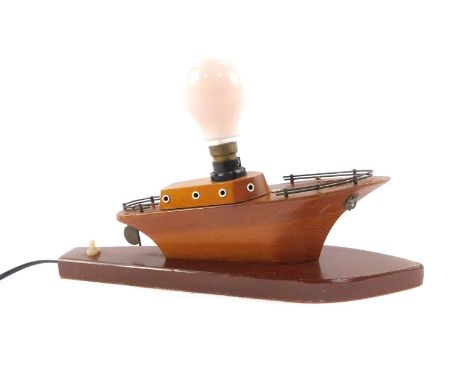 A mid 20thC beech and pine table lamp, carved as a sailing cruiser, raised on a shaped base, 36cm W.