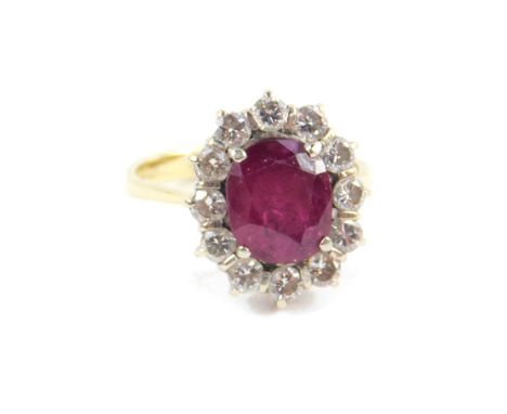 An 18ct ruby and diamond ring, the oval cut ruby, approx 3.5cts, in a surround of twelve diamonds, approx 1.08cts, size N/O, 