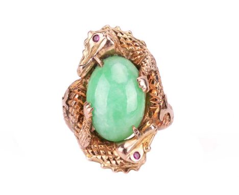 A jade cabochon dress ring, the central oval cabochon jade measuring 16.7 x 11.1mm, encircled by two carved crocodiles with r